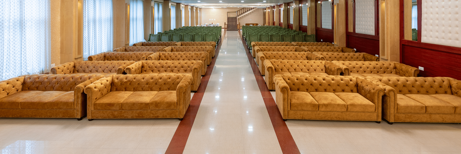 Image of an expansive banquet hall featuring brown and green sofas at DLS Tehri Club Resort.
